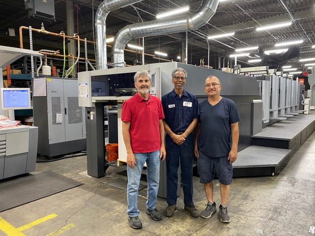 (In the photograph are: (L to R), Paul Heavilin the Prepress/Sheetfed Manager, Tracey Hayden the First Shift Pressman, and Marco Garcia the Second Shift Pressman.)